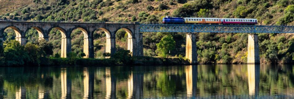 Historic Douro train crossing a stone viaduct over the river